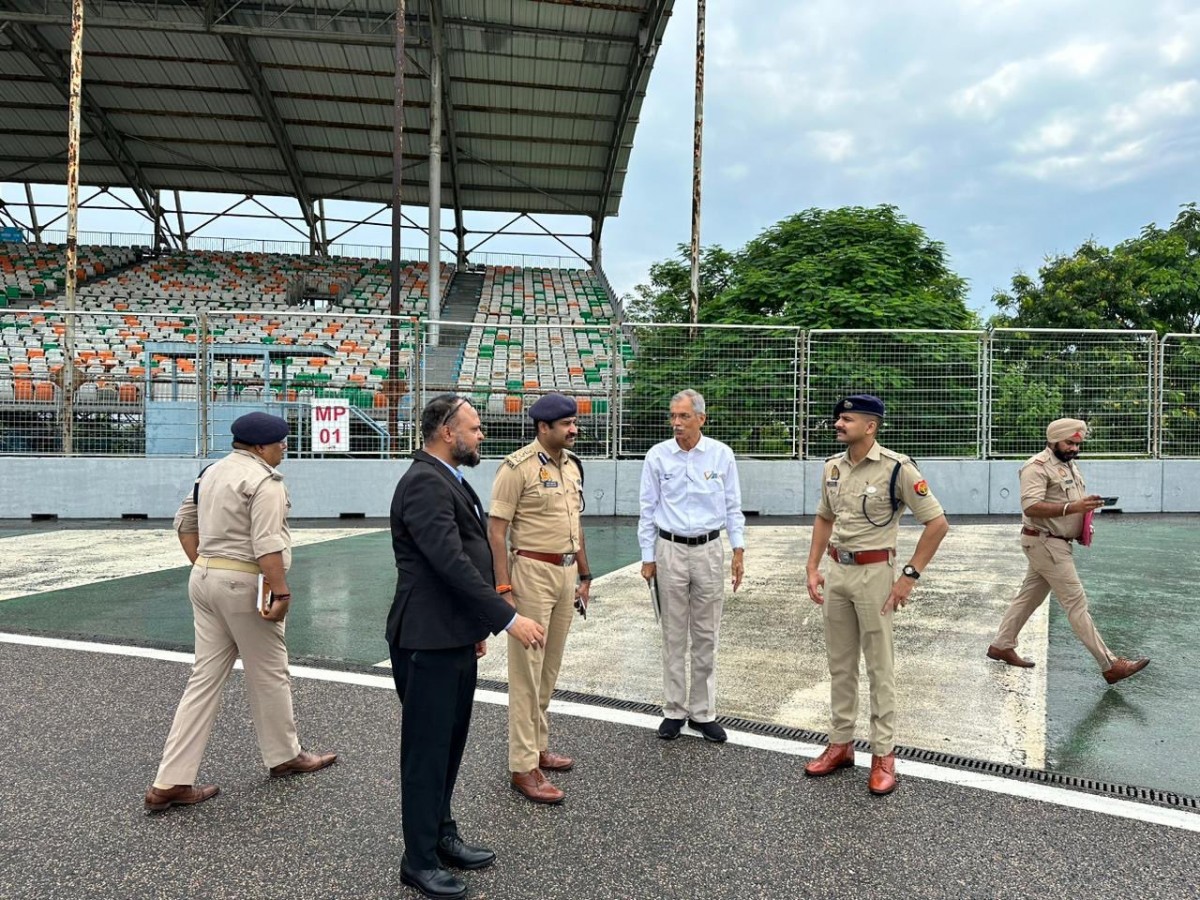 Официальные лица на фоне зоны безопасности 1-го поворота Buddh International Circuit